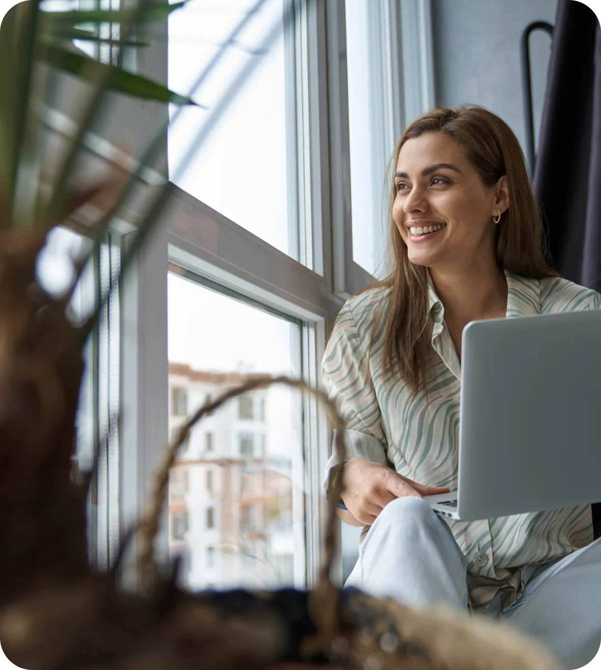 Mulher sorrindo com um celular e um cartão de crédito na mão